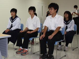 前列、左から制服を着た1人の女子生徒と2人の男子生徒が並んで座っていて、後列も3人が並んで座っている写真