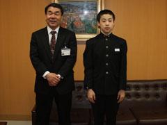 右から制服を着た男子生徒と、スーツを着た男性が立って並んでいる写真