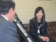 教育長の前で座って話す女子学生の写真