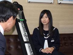 スノーボードを横に座って話す女子学生の写真