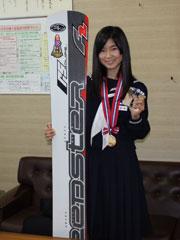 スノーボードを抱え金メダルを首にかけた女子学生の写真