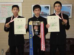 トロフィーと賞状を持ちメダルを掲げている3名の男子生徒の写真