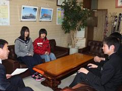 机の周りに座り談笑する教育長と学生の写真