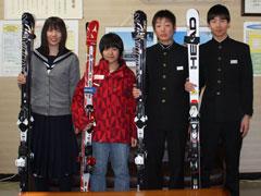 スキー板を抱え写真撮影をする学生たちの写真