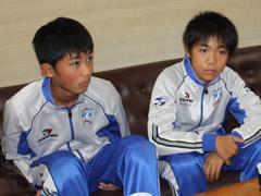 水色と白のジャージ姿の二人の選手たちが椅子に座っている写真