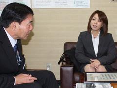 ソファに座りながらスーツ姿の男性と話しているスーツ姿の女性の写真