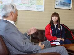 ユニフォームのウインドブレーカー姿で教育長の話を聞く藤原加織選手の写真
