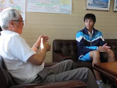 椅子に座り、手振りを交えて話す教育長とそれを聞く鈴木天理選手の写真