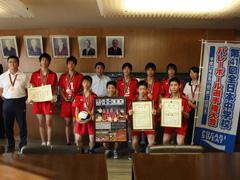 全日本大会に出場したバレーボール部の学生と関係者がメダルをかけ、賞状、新聞、ボール、旗を持ち市長と映った集合写真