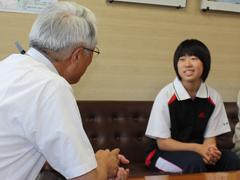 バドミントンの全国大会に出場する学生がユニフォーム姿で教育委員長と対面している写真