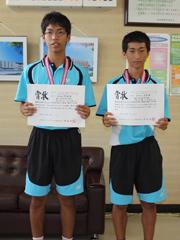 ユニフォームを着た男子ソフトテニス部の学生がメダルをかけ賞状を手にした写真