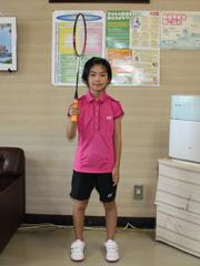 ピンクのユニフォームを着た女子児童がラケットを構えている写真