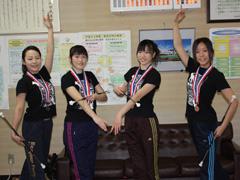 メダルを首からかけポーズをとり写真撮影する女性たちの写真
