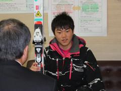 スキー板を片手に話す男性の写真