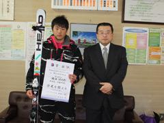 スキー板を片手に賞状を持ち男性の横で記念撮影している写真