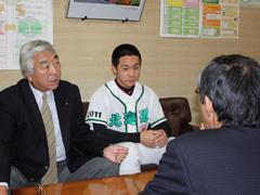 スーツを着た男性とユニフォームを着た男性が並んで座っている写真