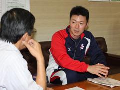 座って話すジャージを着た男性の写真
