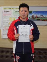 赤と紺のジャージを着た男性が賞状を掲げている写真