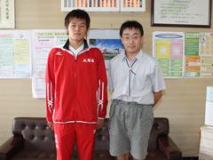 赤いジャージを着た男性と半袖短パンの男性が並んでいる写真