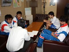 それぞれソファーに座り教育長の話を聞く男子生徒四人の写真