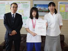 メダルを下げて賞状を持ちながら記念撮影する女子生徒の写真