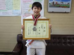 道着姿の小学生が首に銀メダルを下げ賞状を両手で持って撮影されている写真