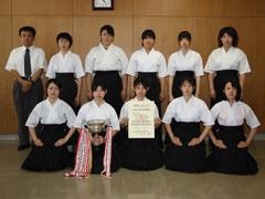 弓道着姿の女子学生達が賞状を両手で持って顧問と並んで撮影されている写真