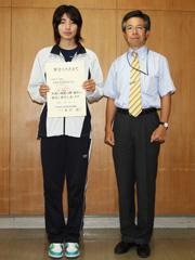 ジャージ姿の女子学生が賞状を両手で持って顧問と並んで撮影されている写真