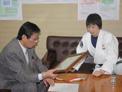 柔道着を着た選手が教育長に賞状を見せている写真