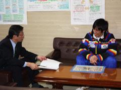 座って教育長と談笑する国体スキージャンプ大会少年の部で優勝した高校生の写真