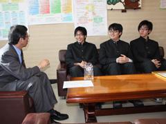 座って教育長と談笑する学生服を着た3人の高校囲碁部のメンバーの写真