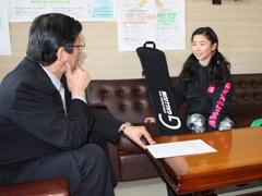 スノーボードをおいて教育長と談笑する小学生スノーボード大会で優勝した女子小学生の写真
