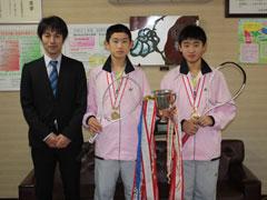 優勝のトロフィーとテニスラケットを持ちポーズを取る男子中学生2人の写真