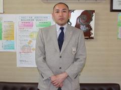 グレイのスーツを着てポーズを取るバンクバーオリンピク女子ボブスレー監督の中学教諭の写真