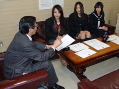 座って教育長と話をする女子学生の写真