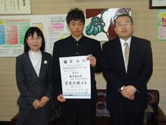 書状を持っている男子学生と両脇に立っている大人二人の写真