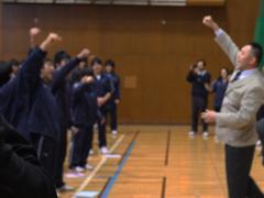 生徒たちと一緒にガッツポーズをする男性の写真