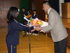 代表の女子生徒から花束を受け取る男性の写真