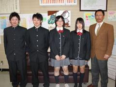 男性2名・女性2名の代表メンバーとその右隣に茶色いスーツの男性が写っている写真