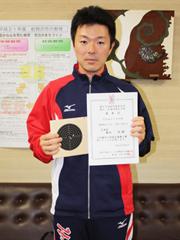 ライフル射撃選手が受賞した表彰状を掲げている写真