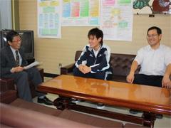 水泳選手の男性が、報告をするために教育長と対談している写真
