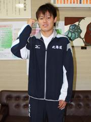 水泳選手の男性が、ユニフォームを身にまといポーズをとっている写真