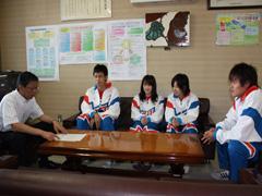 右から、ユニフォームを着た男子生徒と、2人の女子生徒、その左に男子生徒と、机を挟んでワイシャツを来た男性が椅子に座っている写真