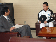岩見沢市の教育長を訪問し、ソファに腰かけて教育長と談笑している高田渉さんを撮影した写真