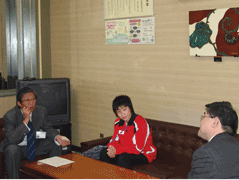 岩見沢市の教育長を表敬する赤い長袖のユニフォームを着ている東野有紗さんが映っている写真