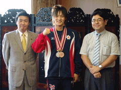 右からワイシャツを来た男性と、ユニフォームを着て胸に2つのメダルをかけている男子生徒、スーツを来た男性が並んで立っている写真