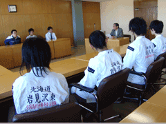 岩見沢市の教育長や教育委員会に訪問し、椅子に腰かけている岩見沢東高校水泳部・少林寺拳法部の皆さんが映っている写真