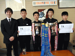 顧問の先生とトロフィーや賞状を持って千葉 亮輔さん、上村 昇平さん、永野 晶暉さん、黒瀬 雅人さんが映っている写真