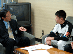 岩見沢市教育長を訪問し、ソファに腰かけているユニフォームを着ている加勢 一心さんが映っている写真