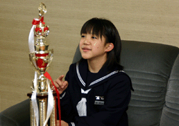 トロフィーと一緒に映る制服を着た女子生徒、木村 友梨香さんの写真